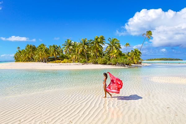 lady holding towel walking through beach in the cook islands