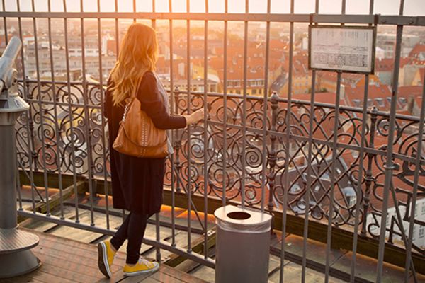 Woman looking out at the city of Copenhagen from a viewing platform at sunset