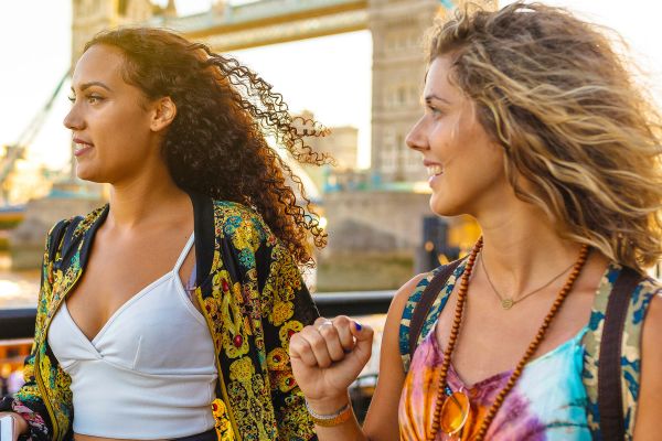 Two women posing in front of Tower Bridge in London at sunset