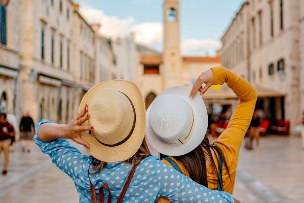 Two Young Female Friends Embracing On The Street In Dubrovnik