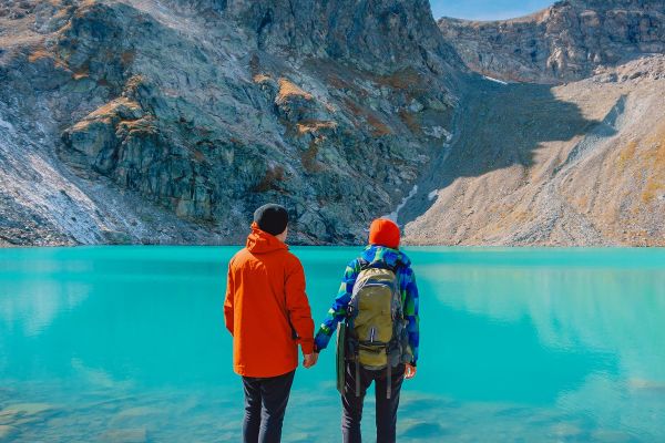 Couple holding hands looking out at a clear blue lake