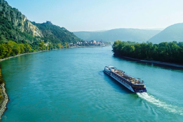 APT river ship cruising past mountain ranges