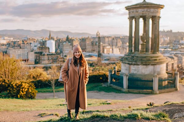 Woman in a long brown coat posing on Carlton Hill in Scotland