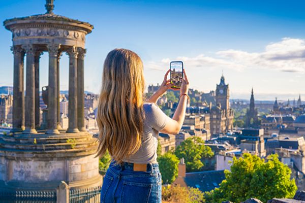 Woman taking a photo of the city of Edinburgh from Calton Hill