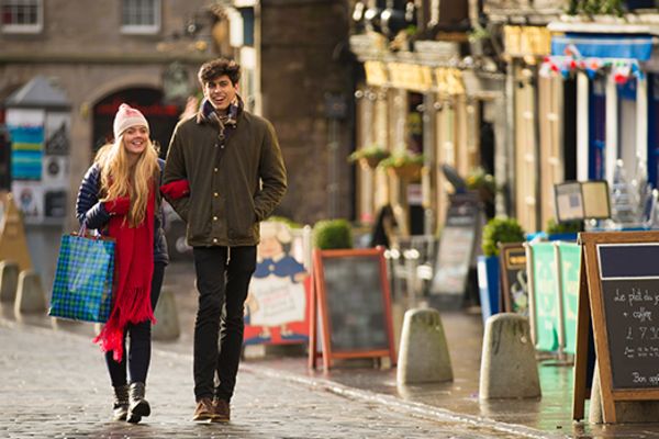 Couple walking down a quiet, cobblestone street in Edinburgh