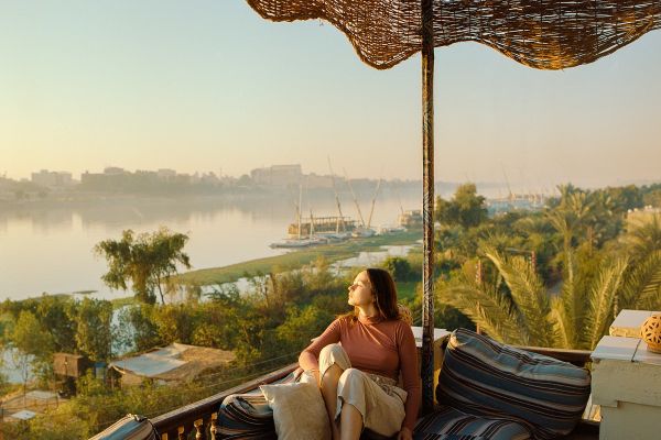 Woman relaxing on a couch overlooking the Nile river at sunset