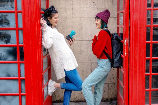 Couple smiling, posing between two red phone booths in England