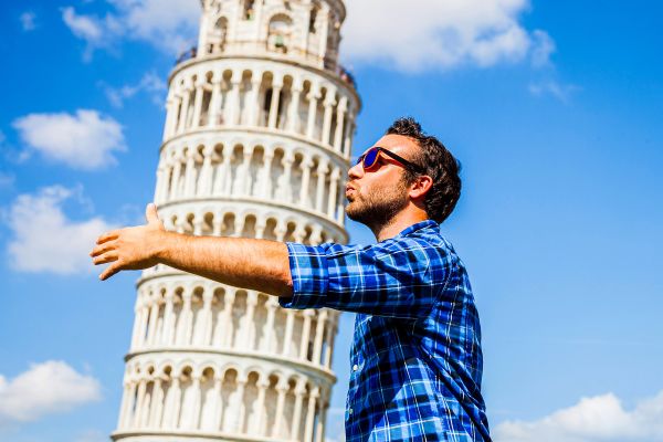 Man doing the "hug the Leaning Tower of Pisa" bit on a sunny day