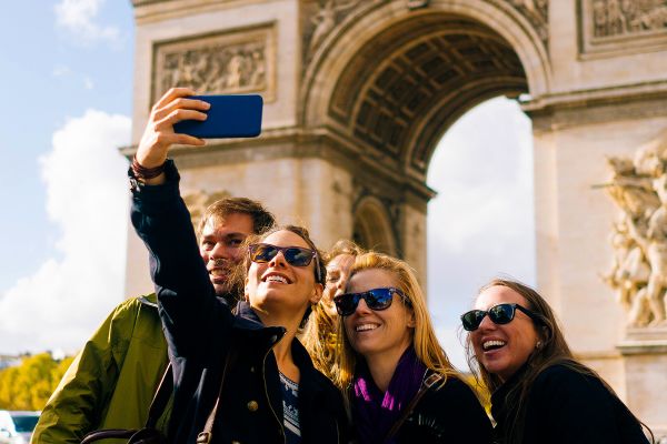 Tourists taking a selfie in front of the Arc De Triomphe in Paris