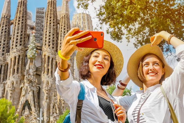 Two women taking a selfie in front of Basílica de la Sagrada Família in Spain