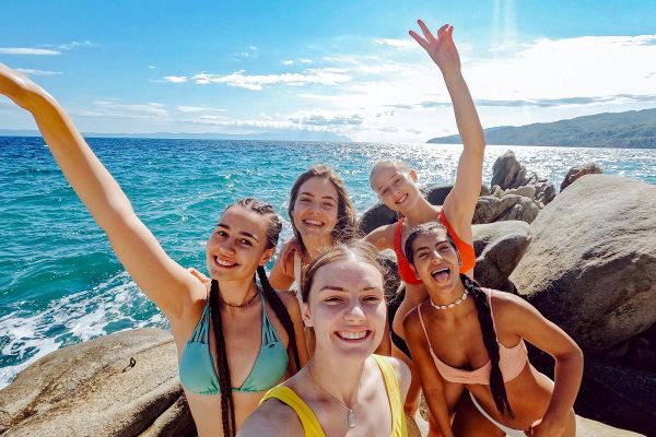 Teenage girls in swimwear posing for a picture in front of the ocean