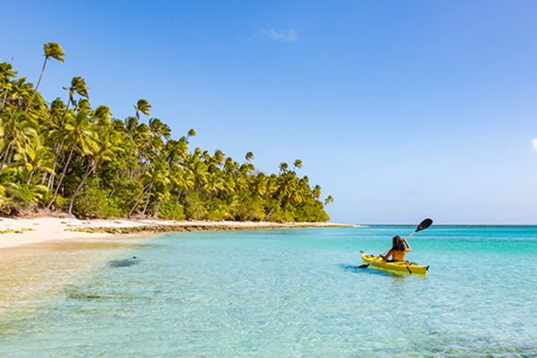 Person in a yellow canoe rowing into the shallows of a tropical island