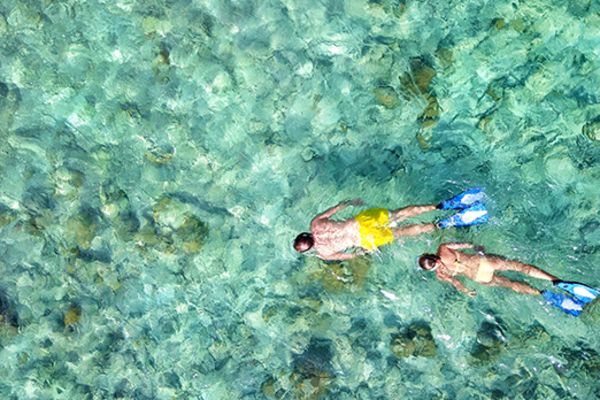 Top down view of two people snorkelling in crystal clear water