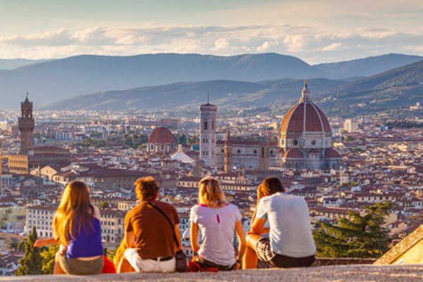 Four friends, sitting on a rooftop looking out at the city of Florence