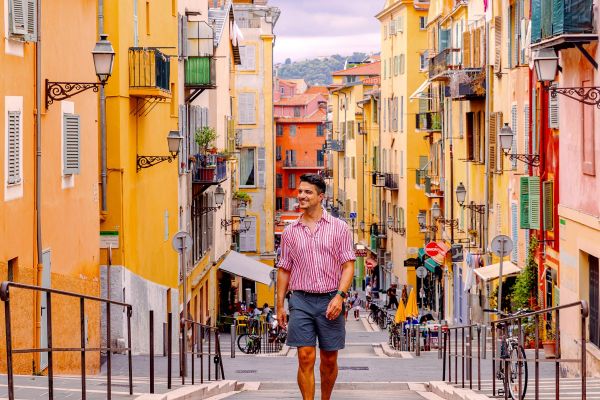 Man in a striped shirt walking through cramped city streets in France