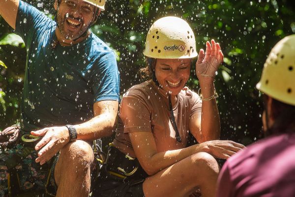 People laughing, wearing helmets, in a jungle