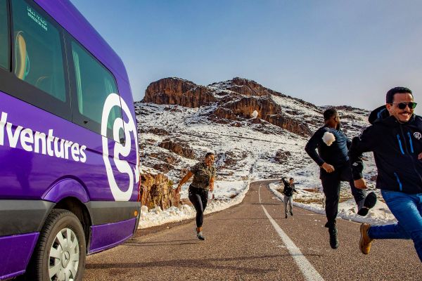 Friends running down a road atop a snowy mountain