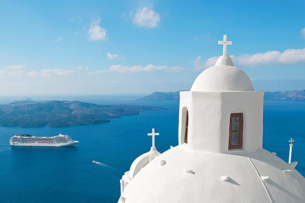 Closeup shot of a white spherical roof with crosses, and a cruise ship in the background