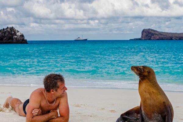 Ecuador, Galapagos Islands, Espanola, tourist and Galapagos sea lion on beach