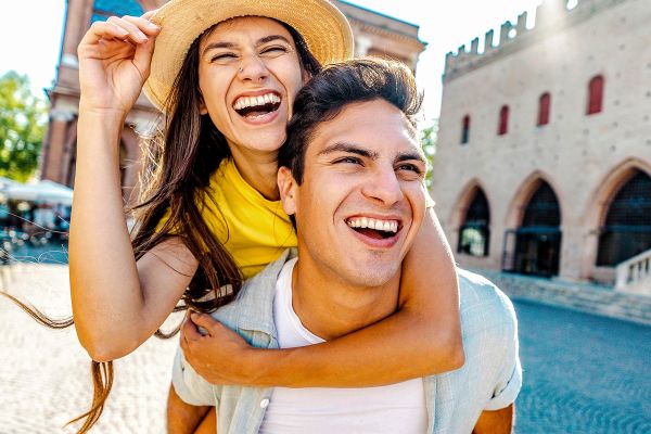 Couple of tourists having fun walking on city street at holiday - Happy friends laughing together on vacation - People and holidays concept