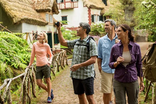 People taking photos in an old fashioned village with thatched roofs, cobblestone paths and stick fencing