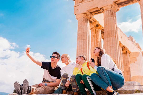 Four friends taking a selfie in front of the Parthenon in Athens, Greece
