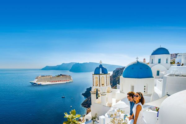 Tw woman wearing long dresses posing in front of sailboats in Greece