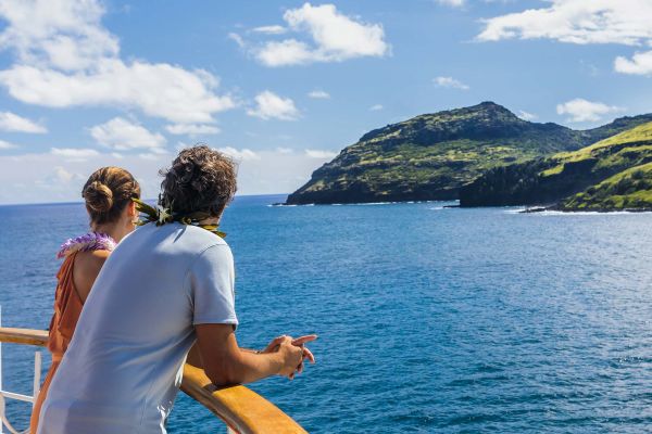 Couple overlooking cruise ship balcony with mountain in background