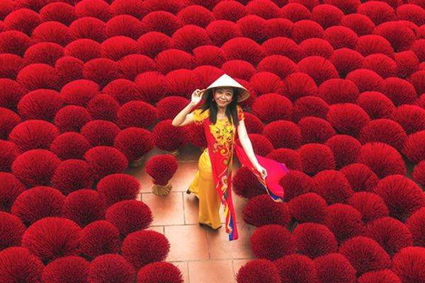 Smiling woman standing in a field of thousands of red incense sticks