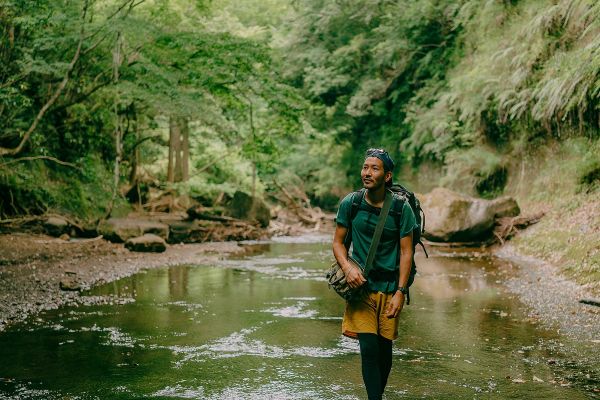 Man hiking through a river in a forest