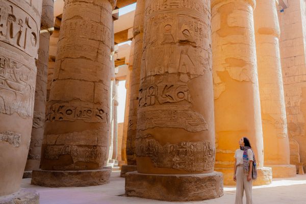 Woman standing next to large columns covered in hieroglyphics in Egypt