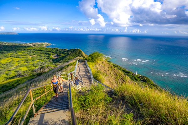 People walking up a steep wooden staircase by the ocean
