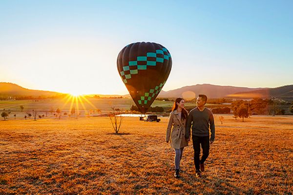 Couple walking away from a hot air balloon at sunset