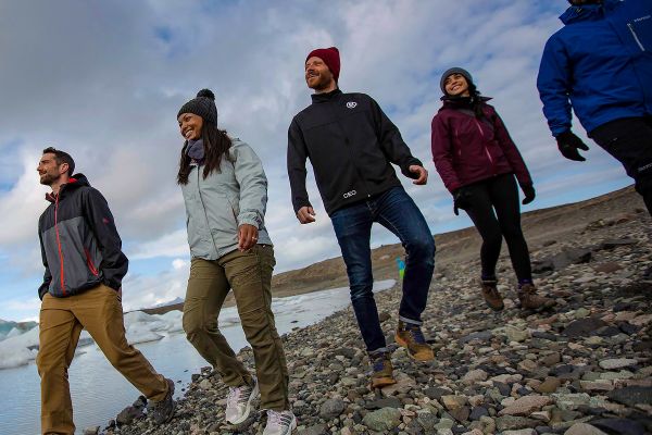 Group of people walking by rocky lake