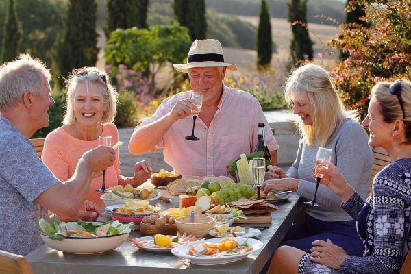 Elderly friends drinking wine around a table outside