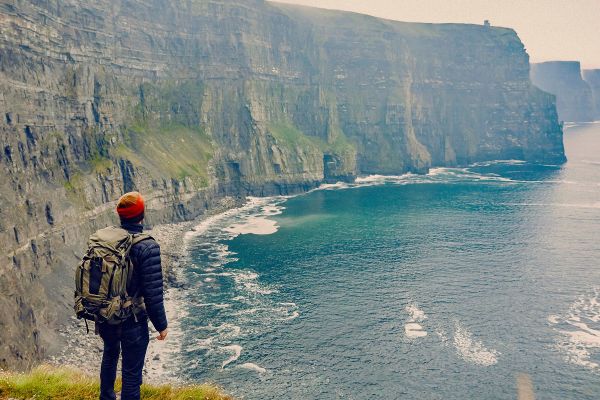 Backpacker looking out at cliffs along the coast of Ireland