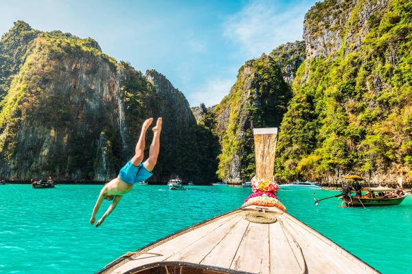 Man jumping off a rowboat in Thailand