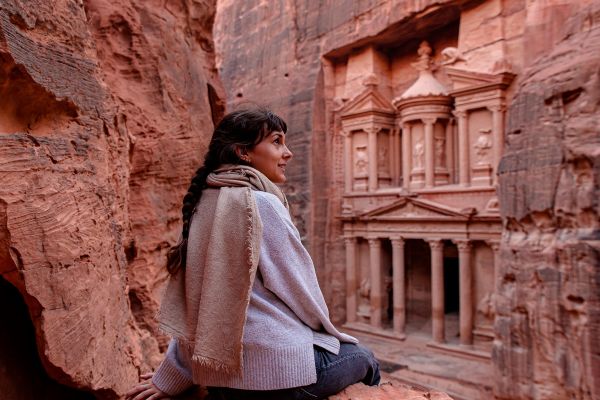 Woman surrounded by rocks looking out at Petra in Jordan
