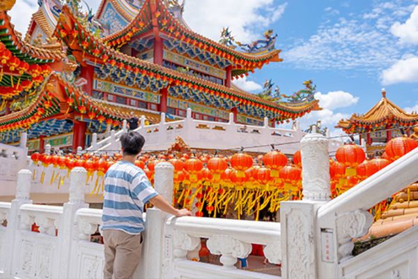 Man standing on railing overlooking temples in Kuala Lumpur