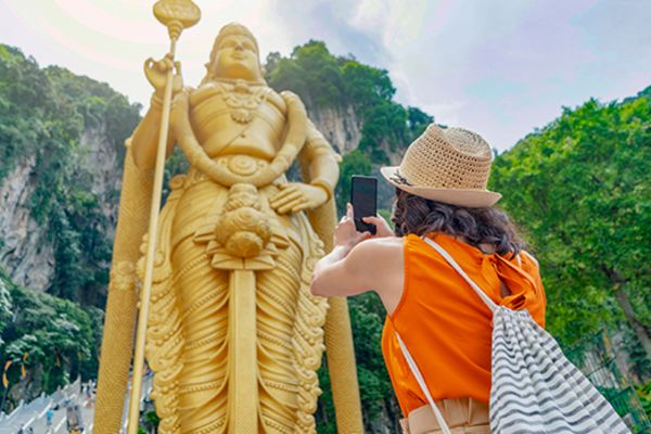 Lady taking photo of tall gold statue in Kuala Lumpur