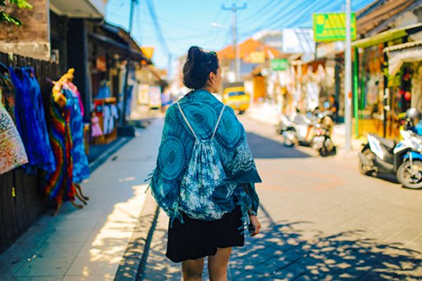 lady walking down road in bali with markets on the side of the road