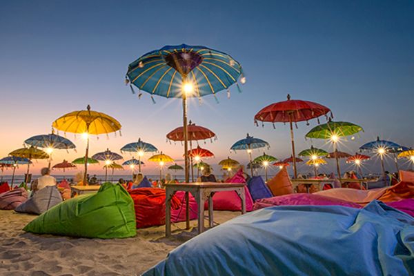 umbrellas with lights and bean bags on beach in bali at dusk