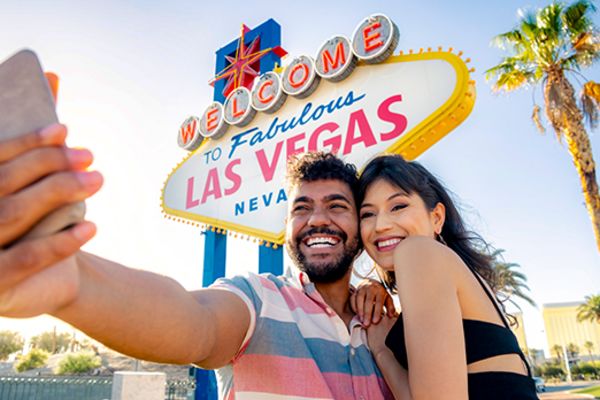 couple taking selfie in front of las vegas sign