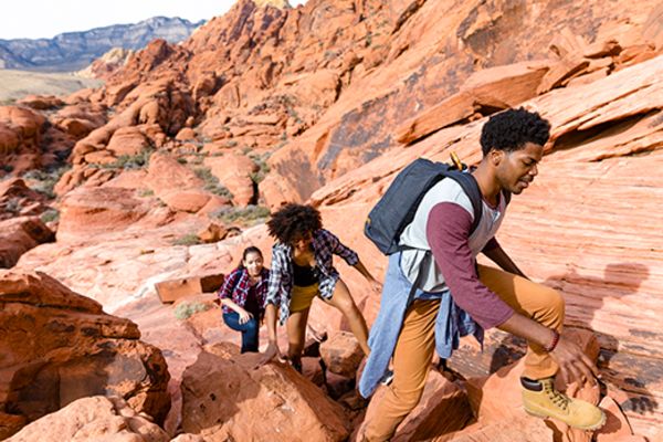 group of 3 friends climbing up rock formations in las vegas