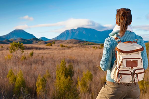 Female backpacker staring out at grassy fields and mountains