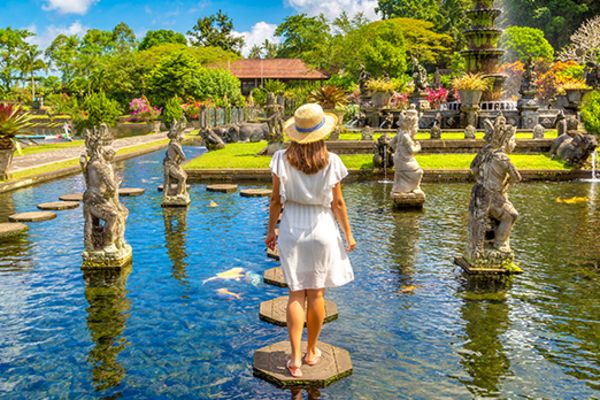 Woman in a white dress standing on a stepping stone in a fountain in Bali