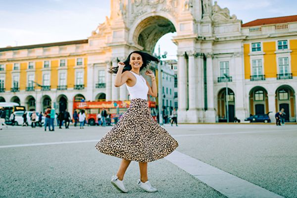 Woman in a leopard print skirt spinning in front of a cream coloured archway