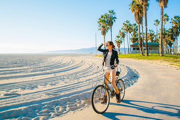 Woman riding a bike alongside a sunny beach