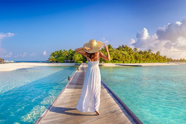 Woman in a white dress walking down a pier towards an island