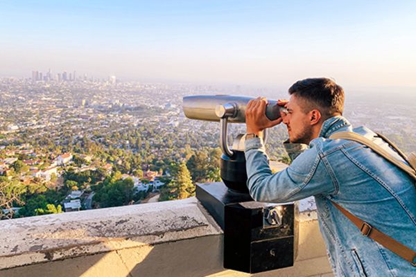 Man looking through binoculars at the city of Los Angeles
